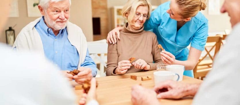 Senior citizens playing a game while staff provides care